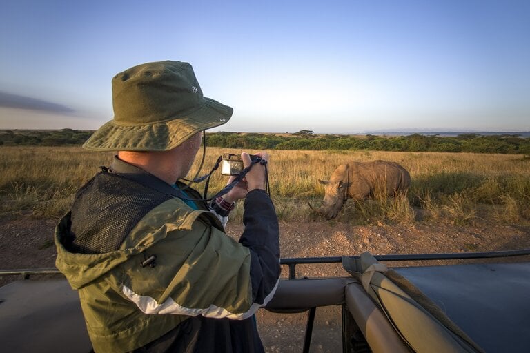A photographer capturing a rhinoceros in the wild.