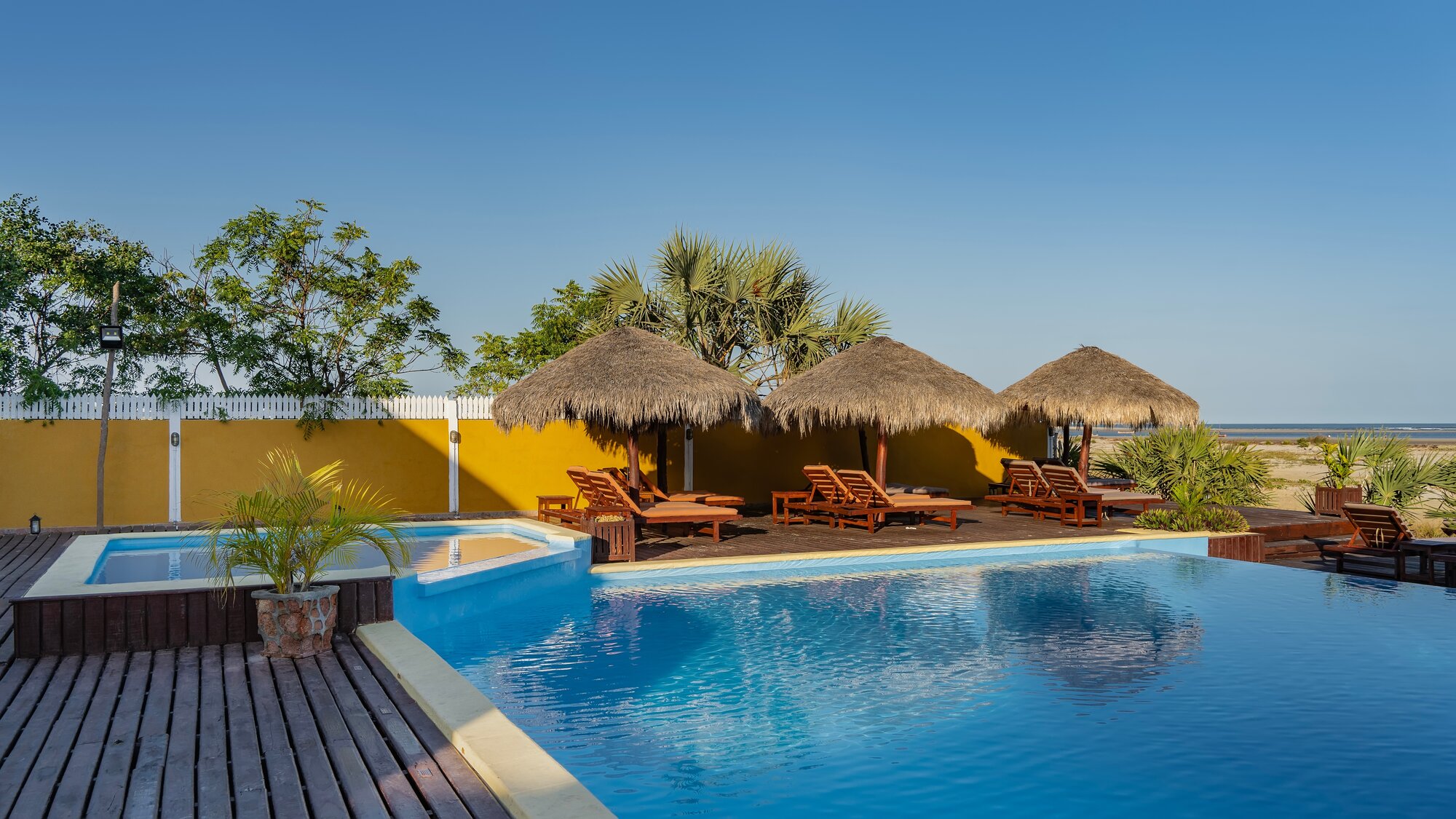 Outdoor pool with huts and sun loungers